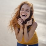 Redheaded woman, laughing happily on the beach
